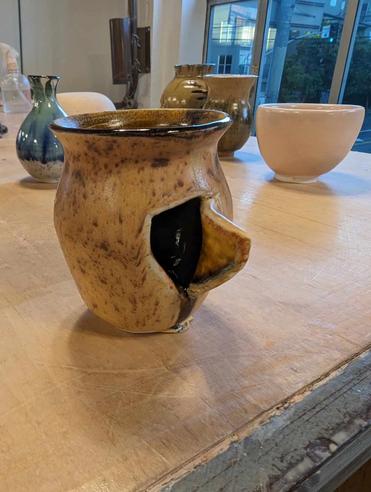 A handmade pot with a hole cut in the side, peeled back to expose the darker interior.
