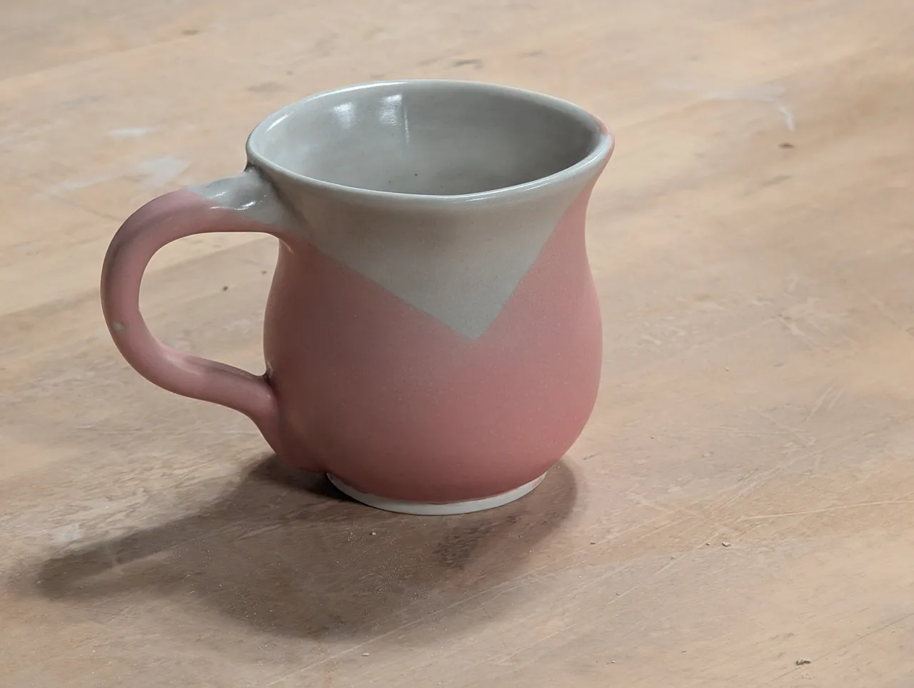 This is probably the only good handle I pulled all year. I liked the glaze on it a lot- it is a light coating of a silver glaze that is mostly translucent over the whole thing, and then a double-dip in pink. I was experimenting with squaring off the mug a little after throwing and trimming, which gave it another pretty interesting feature. Unfortunately, after being in prime rotation as my work coffee mug, it started leaking- a hairline crack that went all the way through the mug. Not sure why, but stressing the clay with the squaring off after it was part dry didn’t help, and then many hot-cold cycles in use as a coffee mug did it in.