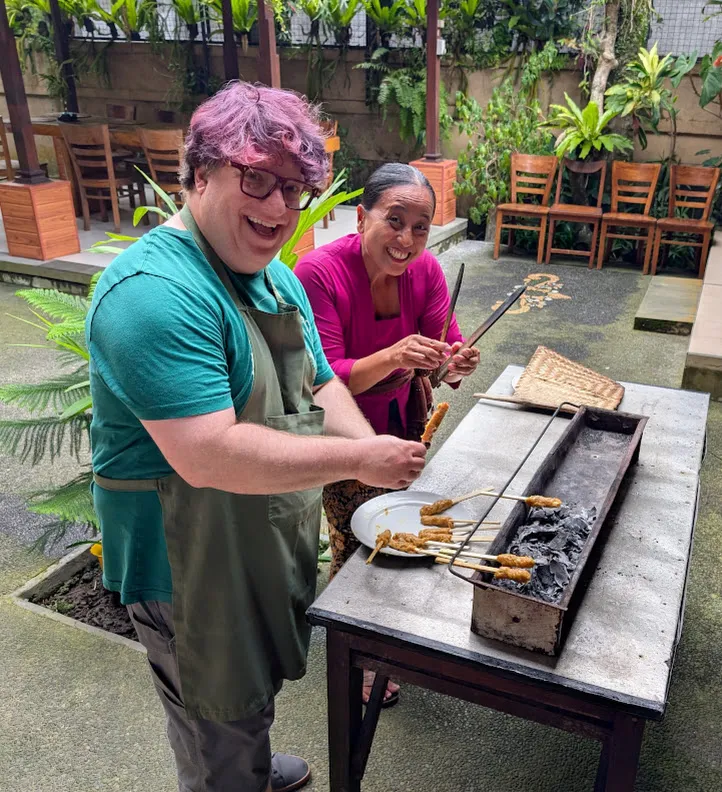 Grilling our completed sate skewers over coconut charcoal. The skewers were the same formfactor as a pair of carry-out chopsticks, but unformed. I feel like they’re the bamboo blanks that go into a chopstick machine.