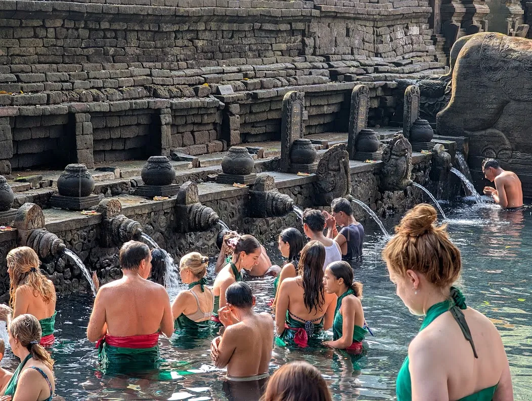 A mixture of local Balinese people and tourists visiting the fountains.